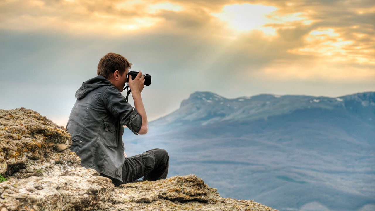 Un turista asiático se tomó una fotografía junto a una montaña en una isla, cuya silueta tenía un gran aprecido a él